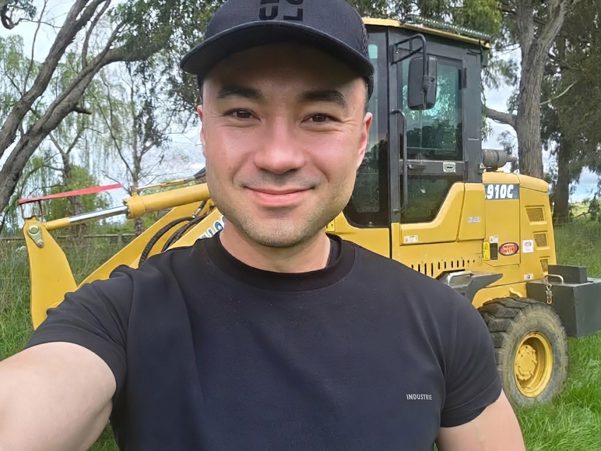 Alexander Wong on the farm in front of a grader
